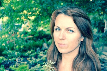 Portrait of a young Ukrainian woman with long brown hair and blue eyes in a flowered summer garden