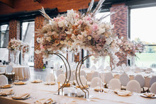 A Large Floral Arrangement Of An Unusual Shape Stands On A Beautiful Festive Table On The Wedding