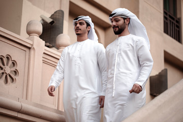 two Arab man wearing traditional clothes and walking in downtown 