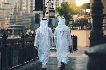 back of two Arabic men walking in Dubai downtown 