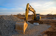 © MaxSafaniuk - Excavator during earthmoving work at open-pit mining on blue sky background. Loader machine with bucket in sand quarry. Backhoe digging the ground for the foundation and for laying sewer pipes