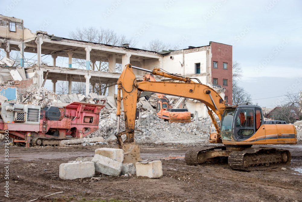 Yellow excavator with bucket at demolition of tall building. Hydraulic ...