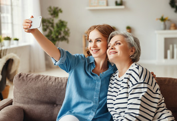 Wall Mural - Happy mother and daughter taking selfie on couch.