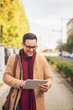 © Jelena - Businessman standing on the street and hold his tablet.