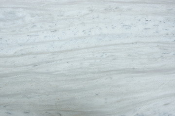  A polished slab of white marble with many gray blurry stripes and dots called Nestos Beige