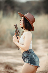 Portrait of asian woman wear cowgirl charactor at the field,Cowboy festival concept,Sexy lady pose for take a picture,Thailand people