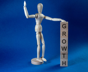 The inscription growth on wooden cubes and wooden man on dark blue background