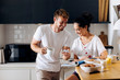 © Westend61 - Happy young couple in the kitchen looking at cell phone