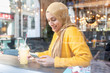 © Westend61 - Portrait of young woman with smoothie and smartphone in a cafe