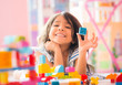 © engagestock - Little Girl Holding Construction Blocks in Hand at Home