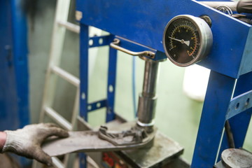 mechanic changing the silent block in the hydraulic press in the car service station