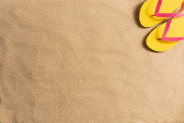 Summer fashion, summer outfit on sand background. Yellow flip flops aon the sand. Flat lay, top view