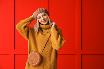 Wall Mural - Young woman in warm sweater on color background