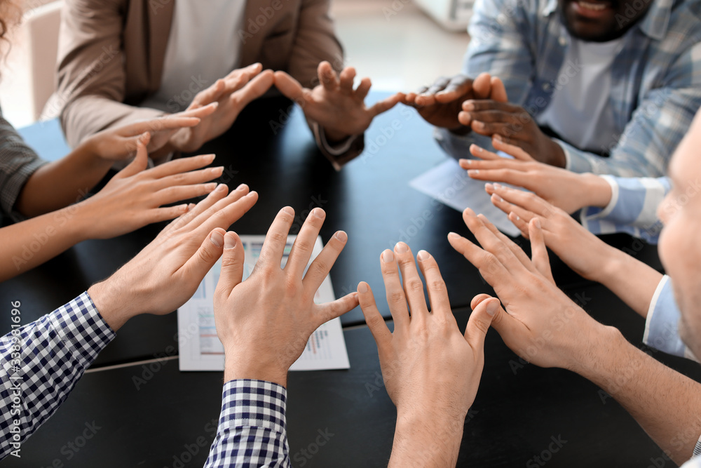 Group of people putting hands together indoors. Unity concept