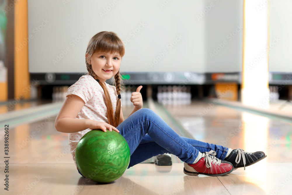 Little girl playing bowling in club
