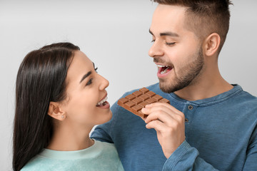 Sticker - Beautiful young couple with tasty chocolate on light background