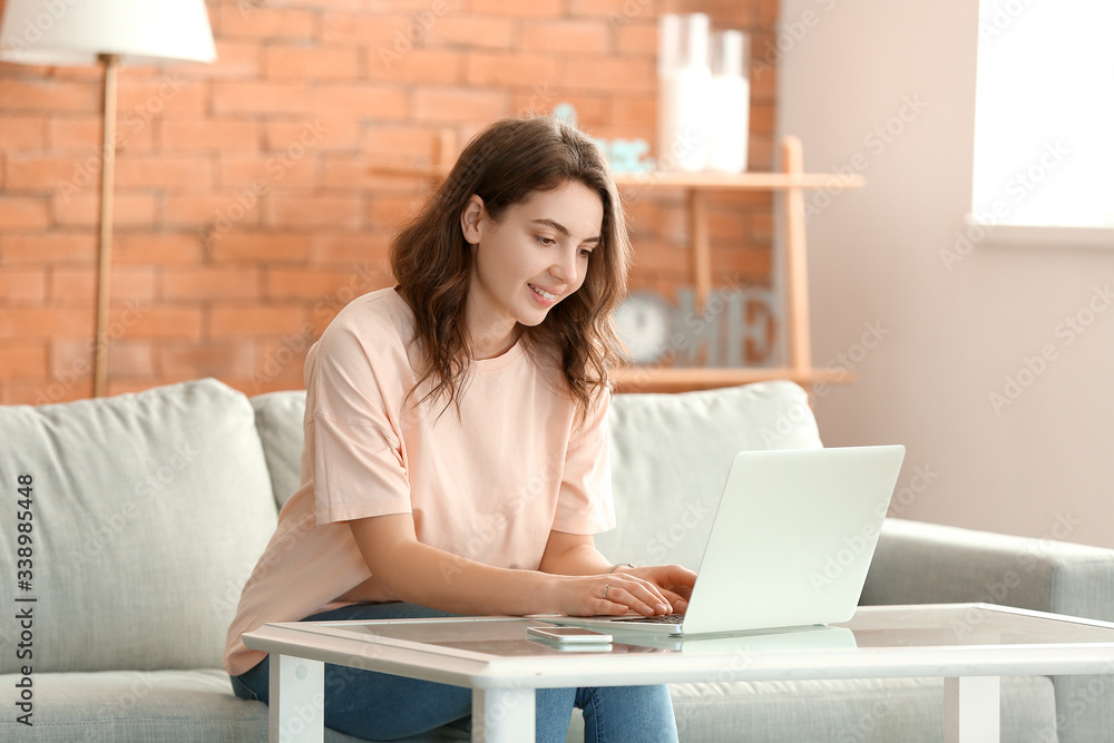 Beautiful young girl working on laptop at home
