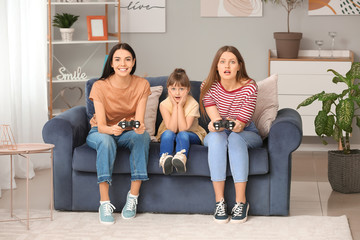 Canvas Print - Happy lesbian couple with little adopted girl playing video game at home