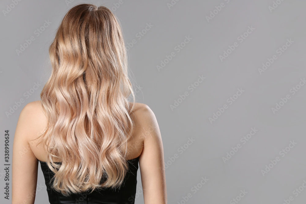 Young blonde with beautiful hair on grey background - obrazy, fototapety, plakaty 