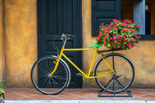 Yellow Vintage Bike With Basket Full Of Flowers Next To An Old Building In Danang, Vietnam