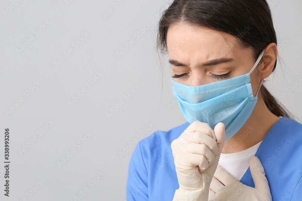 Ill doctor wearing medical mask against grey background