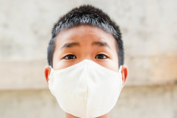 Asian children boy wear N95 mask to protect PM 2.5 dust and air pollution.Children boy in city street wearing face mask protective for spreading of disease Coronavirus.