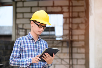 Engineers use a tablets to check  construction. Engineer wearing glasses looking at the tablet.