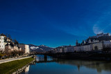 Fototapeta Na drzwi - A river in the middle of two side buildings with the bridge and the reflection of blue sky, Austria
