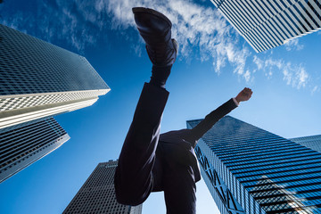 都会でジャンプをする日本人男性ビジネスマン
