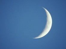 Low Angle View Of Crescent Moon In Blue Sky