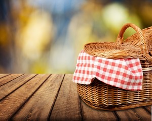 Wall Mural - Picnic basket with a tablecloth on a wooden table