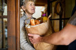 Unrecognizable courier delivering shopping to senior woman.