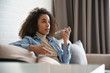 © insta_photos - African girl holding phone speak on speakerphone, using virtual digital voice recognition assistant search, record audio message on smartphone at home. Mobile app ai digital tech assistance concept