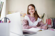 © Halfpoint - Young female student sitting at the table, using laptop when studying.