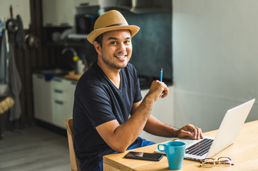 Social distancing concept. Asian handsome man work from home with laptop. Young Casual businessman aged around 30 using laptop for his work.