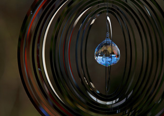 A cut crystal ball hanging in the centre of a decorative metallic mobile