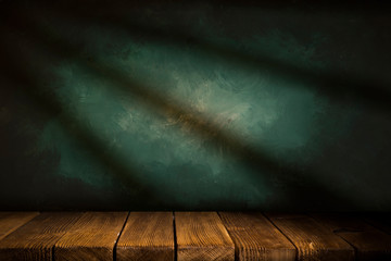 Old wood table with blurred concrete block wall in dark room background.