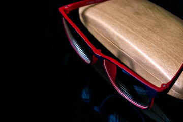 eyeglass with wooden case on top of reflective surface