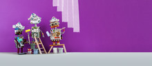 Funny Decorators Robots With Paint Rollers And Buckets, Purple Colored Room Redecoration. Copy Space
