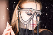 Portrait of a beautiful sexy female with oriental decoration. Model in easterly makeup wore mask of chains decorated diamonds. Girl gags about her skin.