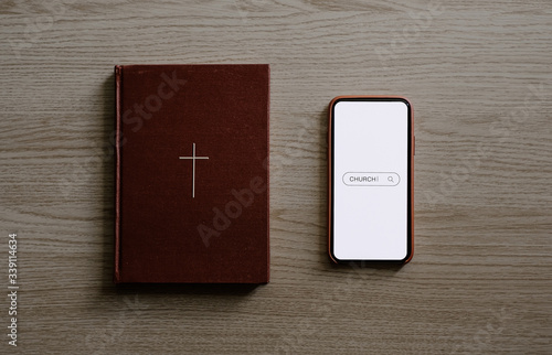 Worship from home, Online church for sunday service, Top view of mobile screen with search icon, bible on wooden table