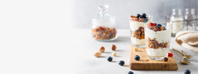 Wall Mural - Granola, cereal breakfast banner. Blueberry parfait in glasses on wooden board on gray background. Cafe, restaurant, confectionery menu. Copy space