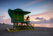 Young Man On Lifeguard Cabin At Sunrise, Miami Beach, USA