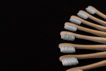 Group of white eco bamboo toothbrushes, on black background. Top view, copy space. Natural organic product for oral hygiene. Dental zero waste and no plastic concept. Safe for the earth.