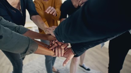 Wall Mural - Multi-ethnic businesspeople putting their hands on top of each other and clapping. Business team making a stack of hands showing unity.
