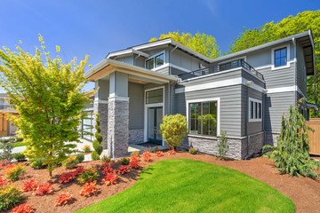 Modern contemporary house exterior with luxury details, landscaping, stone, wood, glass, lots of large windows.