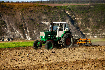 Farmer in tractor preparing land. Agricultural works at farmlands. agricultural work plowing land on a  tractor. Tractor on a farmer field in Moldova, Europe.