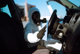 Fototapeta  - Hand of Man in protective suit washing and disinfection of the steering wheel in the car,  prevent infection of Covid-19 virus, contamination of germs or bacteria.
