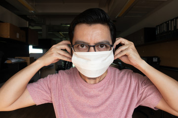 Asian men wearing pink T-shirts and wearing glasses are showing the right masks to prevent germs and viruses. , The concept of epidemic control of covid19