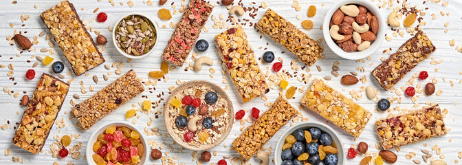 Wall Mural - Cereal healthy snack. Granola bar with nuts and dry fruit berries. Diet food. Protein muesli bars isolated on wood background. Sport oatmeal bar, top view, closeup, banner